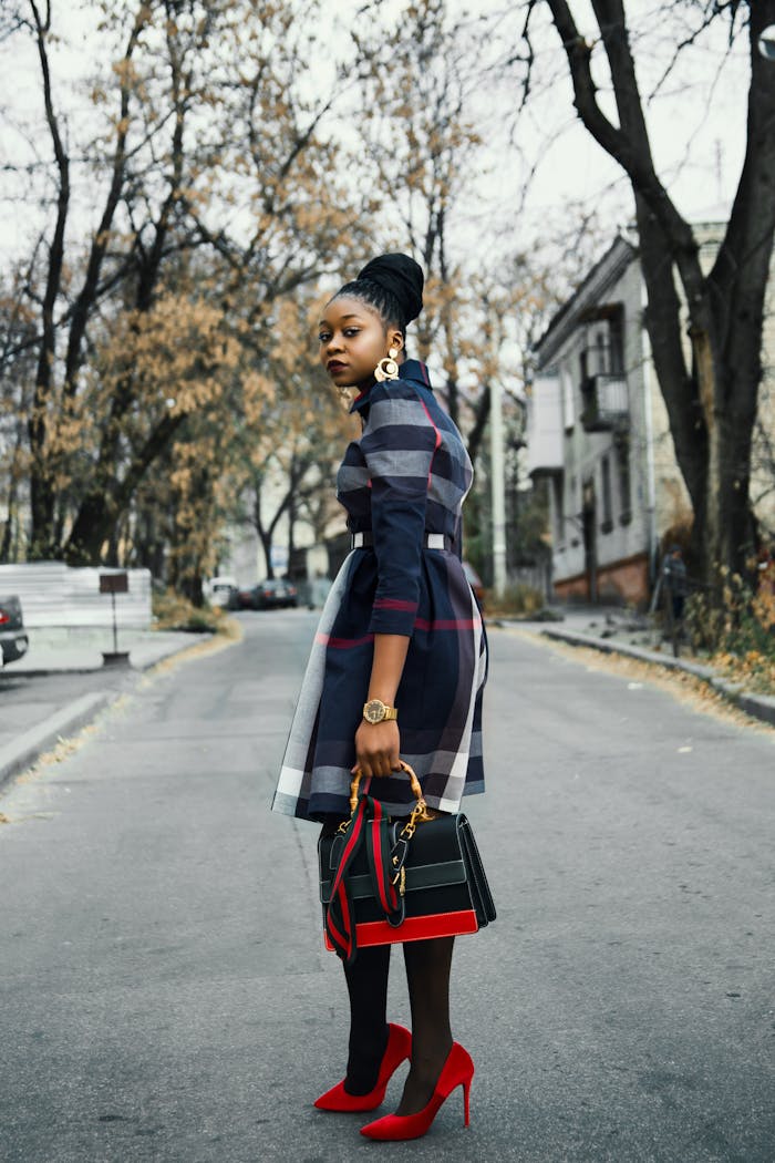 gallery-02 Stylish African American woman poses outdoors with handbag and red shoes.